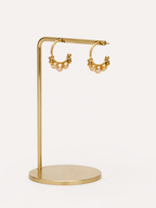 Close-up of 4mm gold cultured freshwater baroque pearls clustered on gold creole hoop earrings