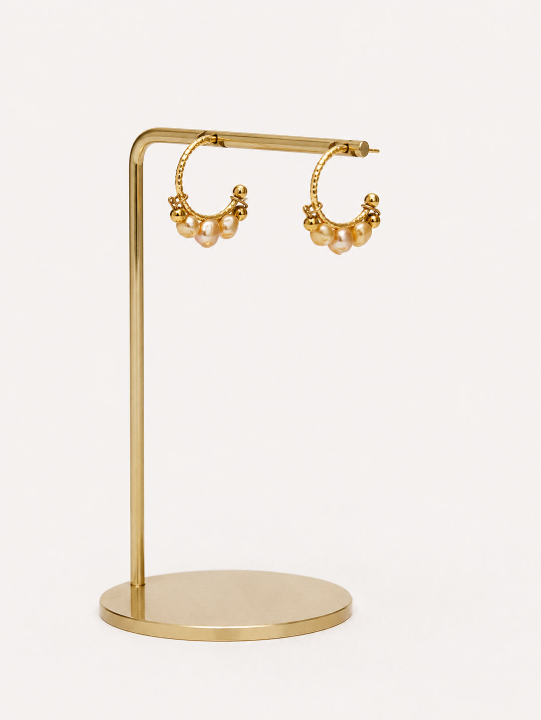 Close-up of 4mm gold cultured freshwater baroque pearls clustered on gold creole hoop earrings
