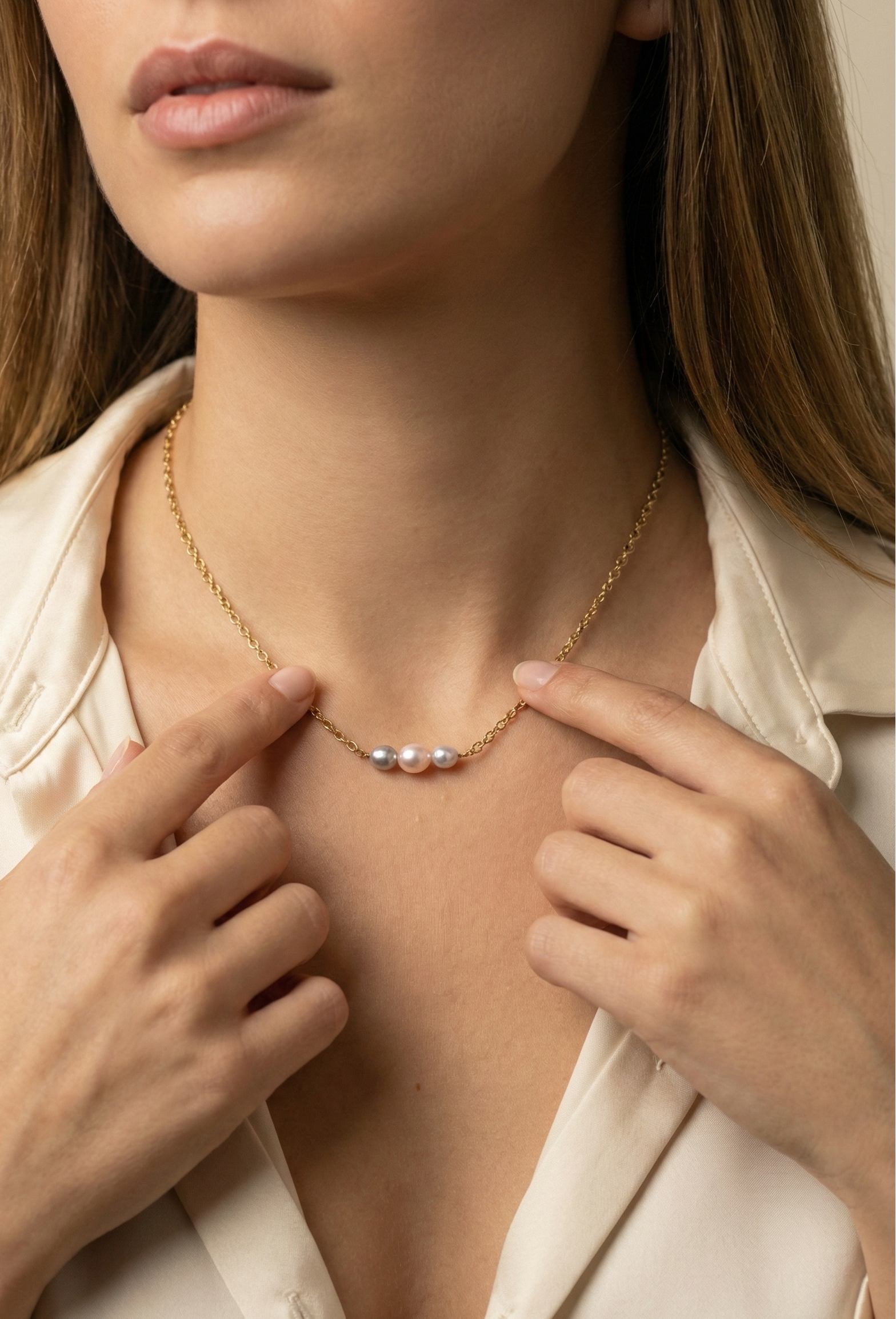 Delicate gold link chain necklace featuring a trio of pearls: a central oval pink pearl flanked by two smaller, irregular grey baroque pearls