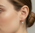 Close-up of a woman's ear wearing a gold hoop earring with a pearl accent.