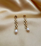 Gold rectangular link chain drop earrings featuring luminous white oval pearls on a beige silk background. Handcrafted Parisian pearl jewelry