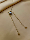 Gold necklace with a pendant on a beige fabric background