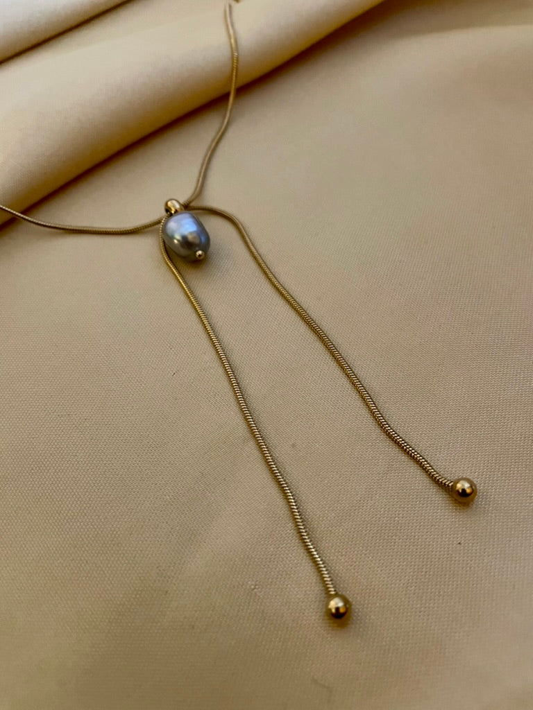 Gold necklace with a pendant on a beige fabric background
