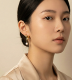 Woman wearing Alizee spiral gold drop earrings with white baroque pearls. Bohemian chic pearl jewelry styled for everyday elegance.