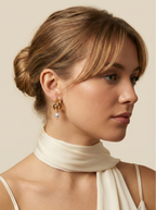 Model wearing chunky 18k gold split hoop earrings with white pearl dangles. Close-up side profile showing ear styling and jewelry scale