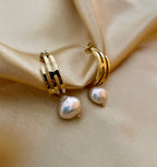 Gros plan sur des boucles d'oreilles pendantes en perles baroques blanches avec fermoir en or