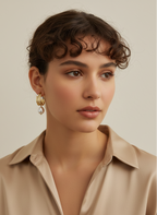 Gros plan sur des boucles d'oreilles pendantes en perles baroques blanches avec fermoir en or, portées par un mannequin