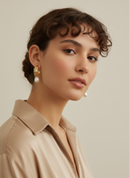 Gros plan sur des boucles d'oreilles pendantes en perles baroques blanches avec fermoir en or, portées par un mannequin