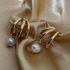 Macro detail of high-luster white pearl charm attached to a polished gold triple-row hoop earring