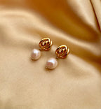 Gold pearl drop earrings featuring a chunky gold knot design and genuine white pearls. Modeled on an ear to show scale and fit
