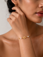 Woman wearing a dainty gold sun charm bracelet with grey baroque freshwater pearls and polished gold beads