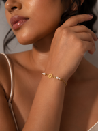 Woman wearing a dainty gold sun charm bracelet with petite white baroque freshwater pearls