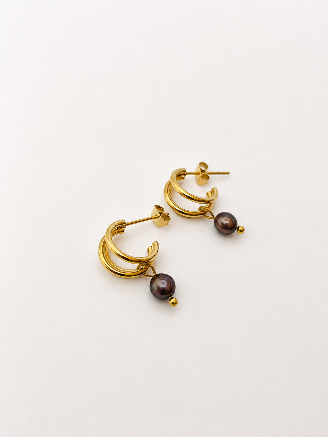 Pair of small gold triple-hoop earrings with 4 mm dark baroque freshwater pearl drops.