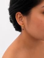 Woman wearing a small gold triple-hoop earring with a 4 mm dark baroque freshwater pearl drop