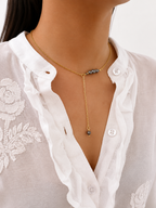 Woman wearing a gold lariat Y-necklace with graduated dark freshwater pearls and a pearl drop pendant.