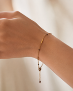 Close-up of a delicate gold bracelet with 2 mm dark grey baroque freshwater pearls worn on the wrist
