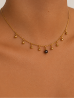 Close-up of a gold bead charm necklace with a 6 mm dark grey cultured freshwater pearl worn on the neck.