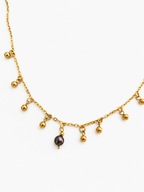 Gold charm necklace with a 6 mm dark grey freshwater pearl and multiple suspended gold bead accents.