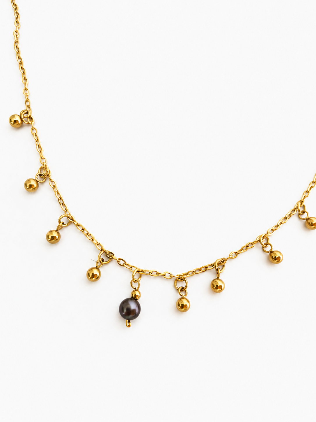 Gold charm necklace with a 6 mm dark grey freshwater pearl and multiple suspended gold bead accents.