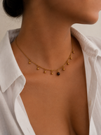 Front view of a gold bead charm necklace with a 6 mm dark grey freshwater pearl worn on the neck