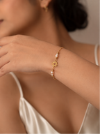 Delicate gold sun charm and white freshwater pearl bracelet styled on the wrist