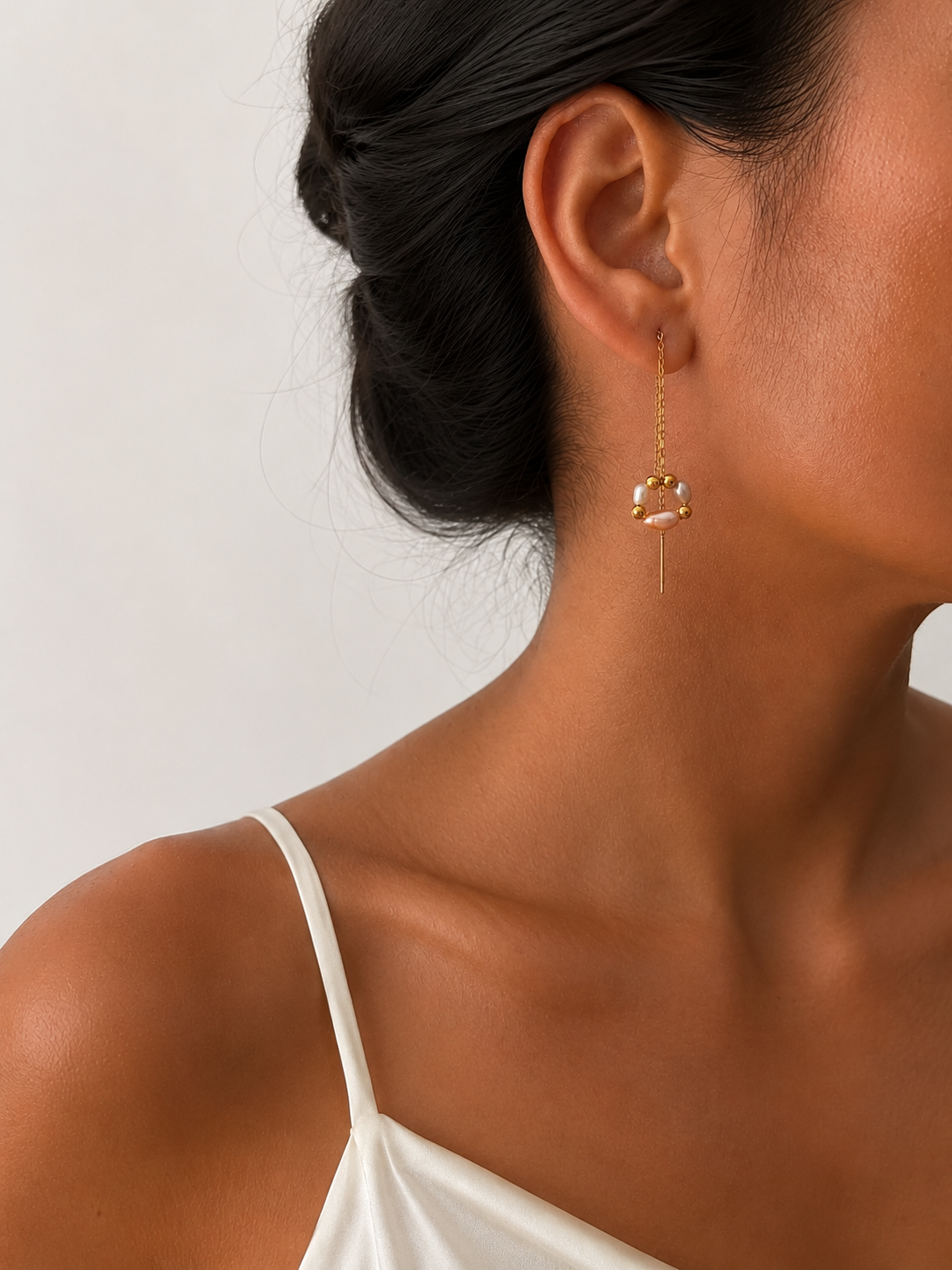 Side profile of a woman wearing a delicate freshwater pearl bouquet threader drop earring