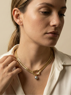 Gold snake chain necklace with a grey baroque pearl pendant. Elegant knotted gold choker styled on a woman for a Parisian chic jewelry look