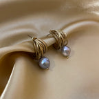 Editorial jewelry portrait showing an elegant grey pearl drop earrings with chunky gold hoops