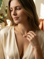 Woman wearing a luxury gold link necklace with a large organic baroque pearl