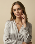 Close-up of a young woman wearing a dainty gold chain necklace featuring a large central baroque white pearl and two smaller accent pearls with gold spacers