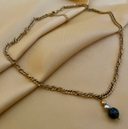 Elegant gold chain necklace with a round black pearl pendant worn