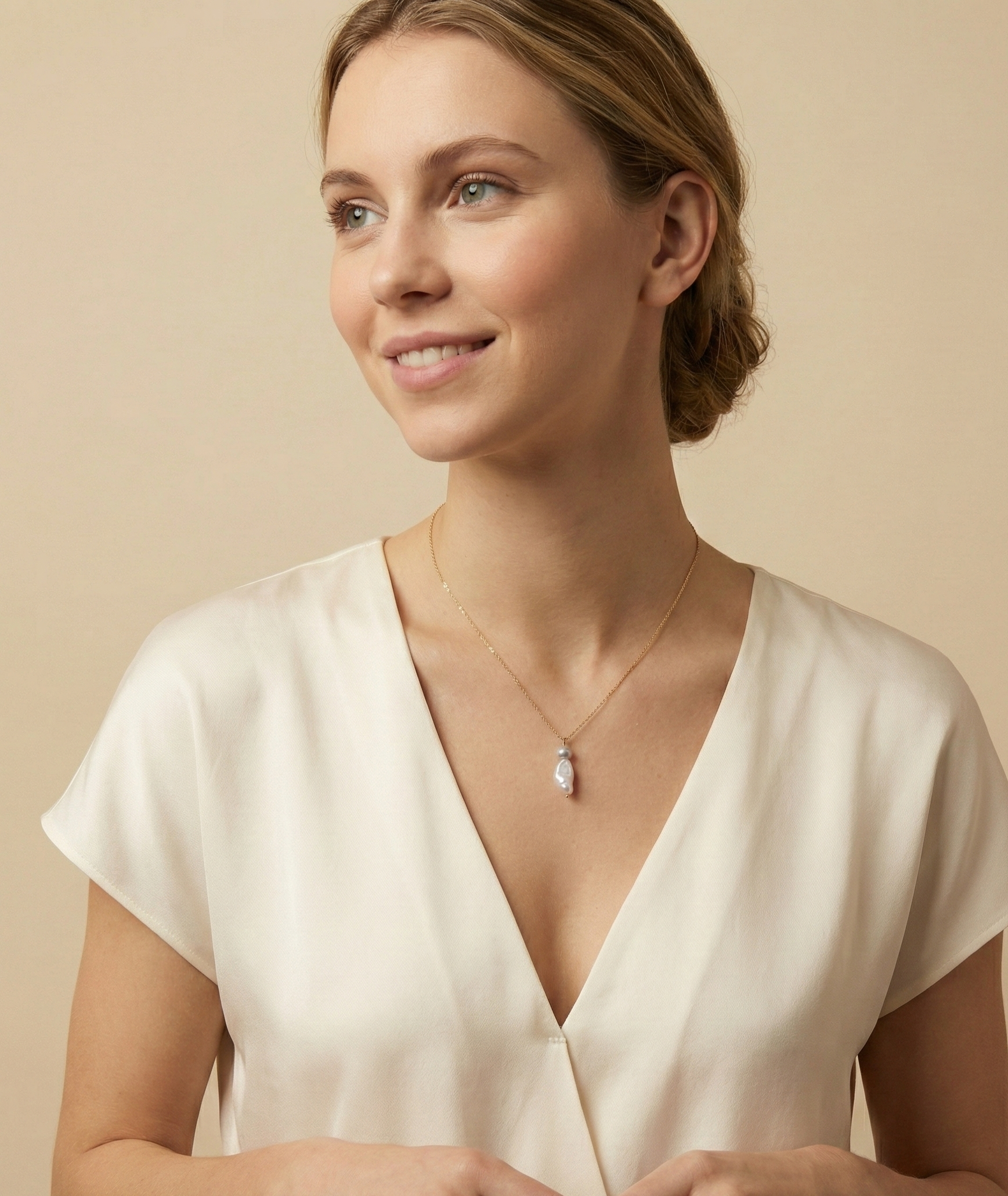 A unique two-tone pearl drop necklace on a gold chain, showcasing a shimmering white organic keshi pearl and a metallic silver-grey baroque pearl resting on the collarbone.