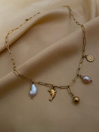 gold paperclip chain necklace featuring a white keshi pearl, gold dolphin charm, pink baroque pearl, and gold sunflower charm
