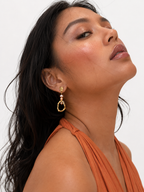 Woman wearing a sculptural gold droplet earring with 4 mm gold and pink baroque freshwater pearls