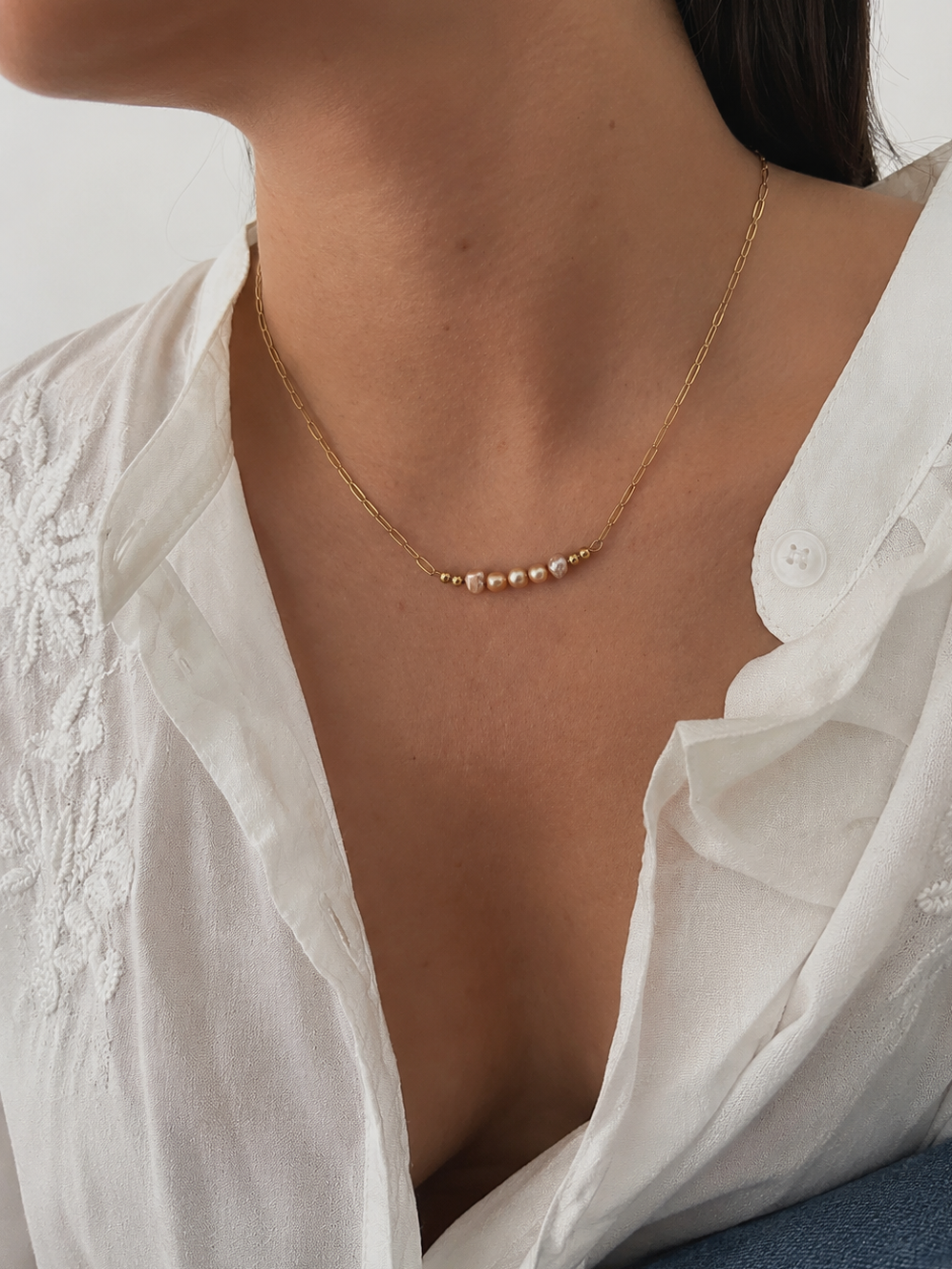 Woman wearing a delicate gold necklace with pink and gold Keshi freshwater pearls and polished gold beads