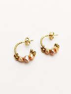 Close-up of gold creole hoop earrings with pink and gold baroque freshwater pearls and polished gold beads.