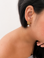Side view of a gold Celtic knot earring with a grey baroque freshwater pearl drop worn on the ear