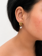 Woman wearing a gold Celtic knot drop earring with a 10 mm grey baroque freshwater pearl.