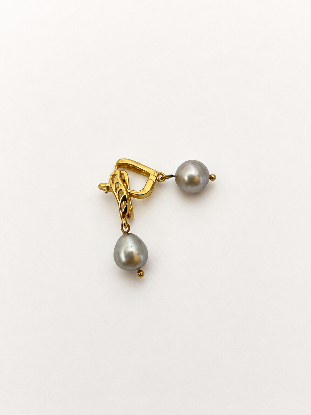 Angled view of gold drop earrings with organic grey baroque freshwater pearl pendants