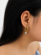 Woman wearing a sculptural gold droplet earring with a grey baroque freshwater pearl drop