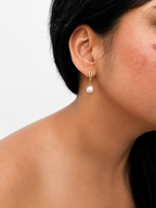Woman wearing a gold drop earring with a 10 mm grey baroque freshwater pearl.
