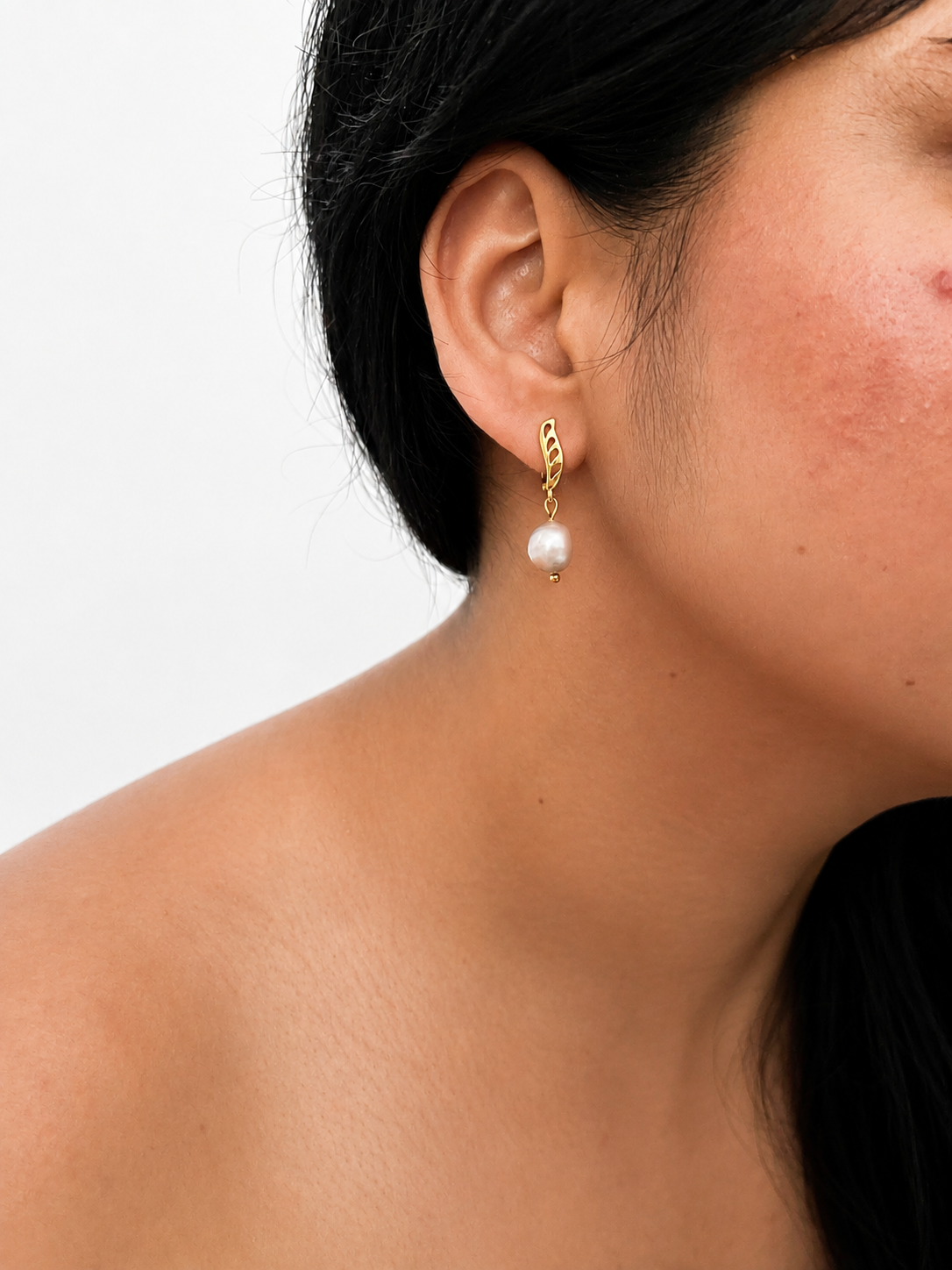 Woman wearing a gold drop earring with a 10 mm grey baroque freshwater pearl.