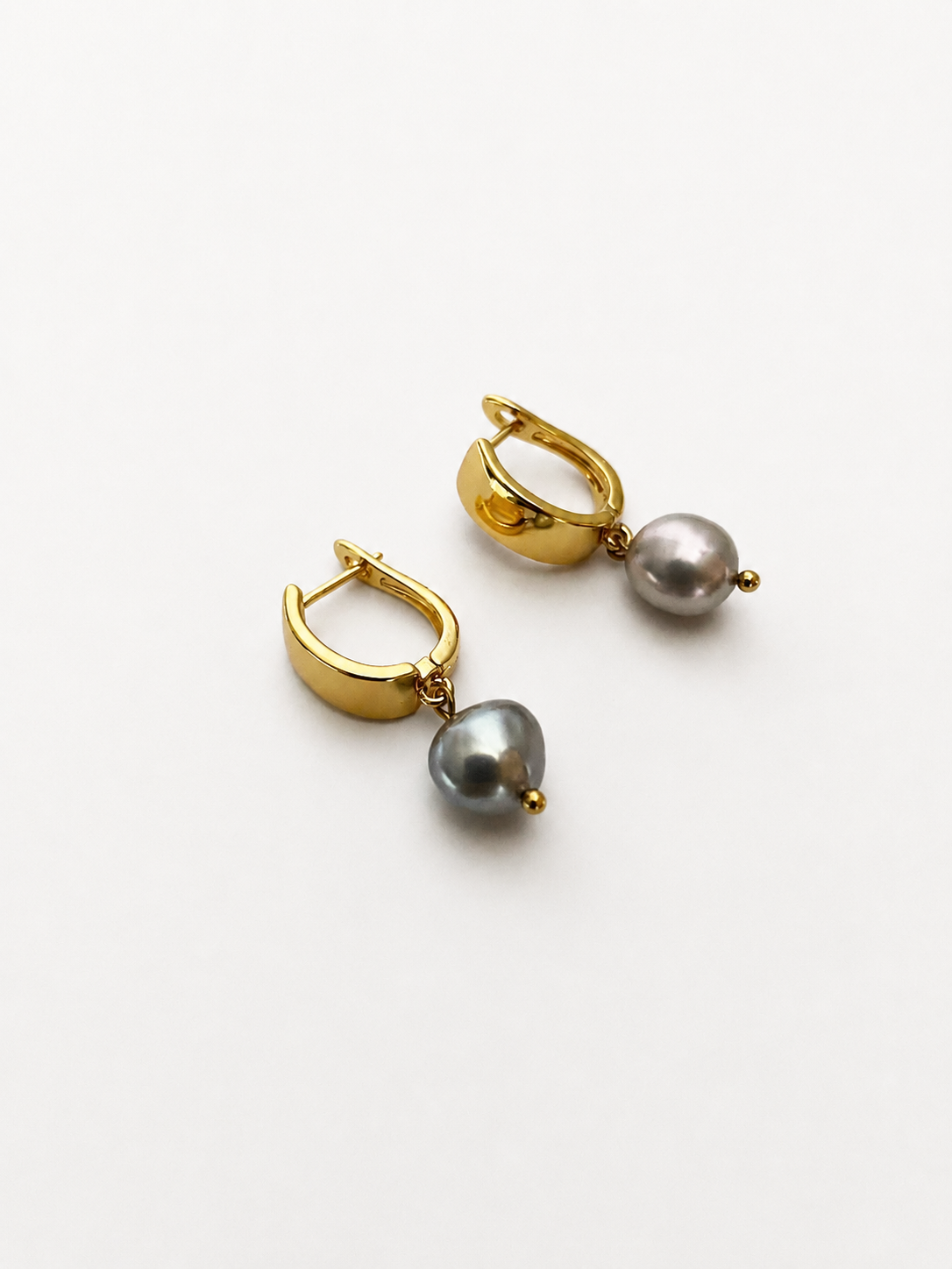Pair of gold huggie hoop earrings with 10 mm grey baroque freshwater pearl drops.