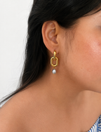 Woman wearing a gold link drop earring with a 10 mm grey baroque freshwater pearl.
