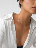 Woman wearing a gold rose station necklace with 4 mm grey baroque freshwater pearls