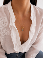 Lifestyle view of a gold lariat necklace with a grey baroque freshwater pearl and sculptural toggle clasp.