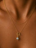 Close-up of a gold lariat Y-necklace with a 10 mm grey baroque freshwater pearl and toggle detail worn on the neck.