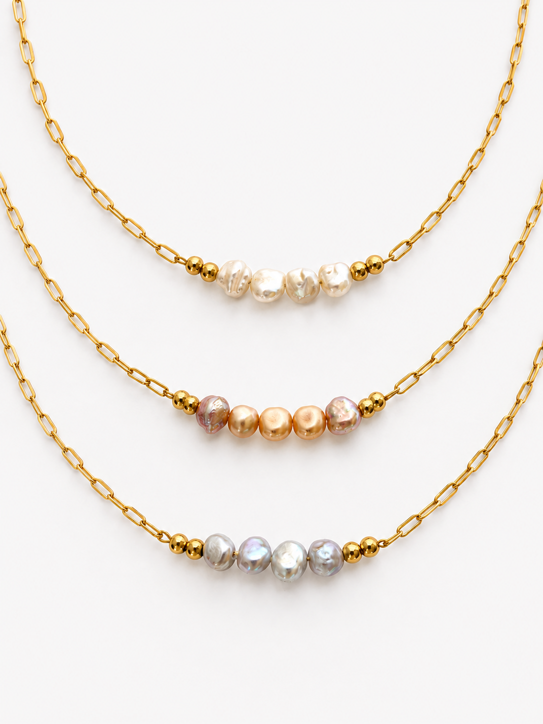 White, pink and grey baroque freshwater pearl necklaces with elongated gold chains and bead accents.
