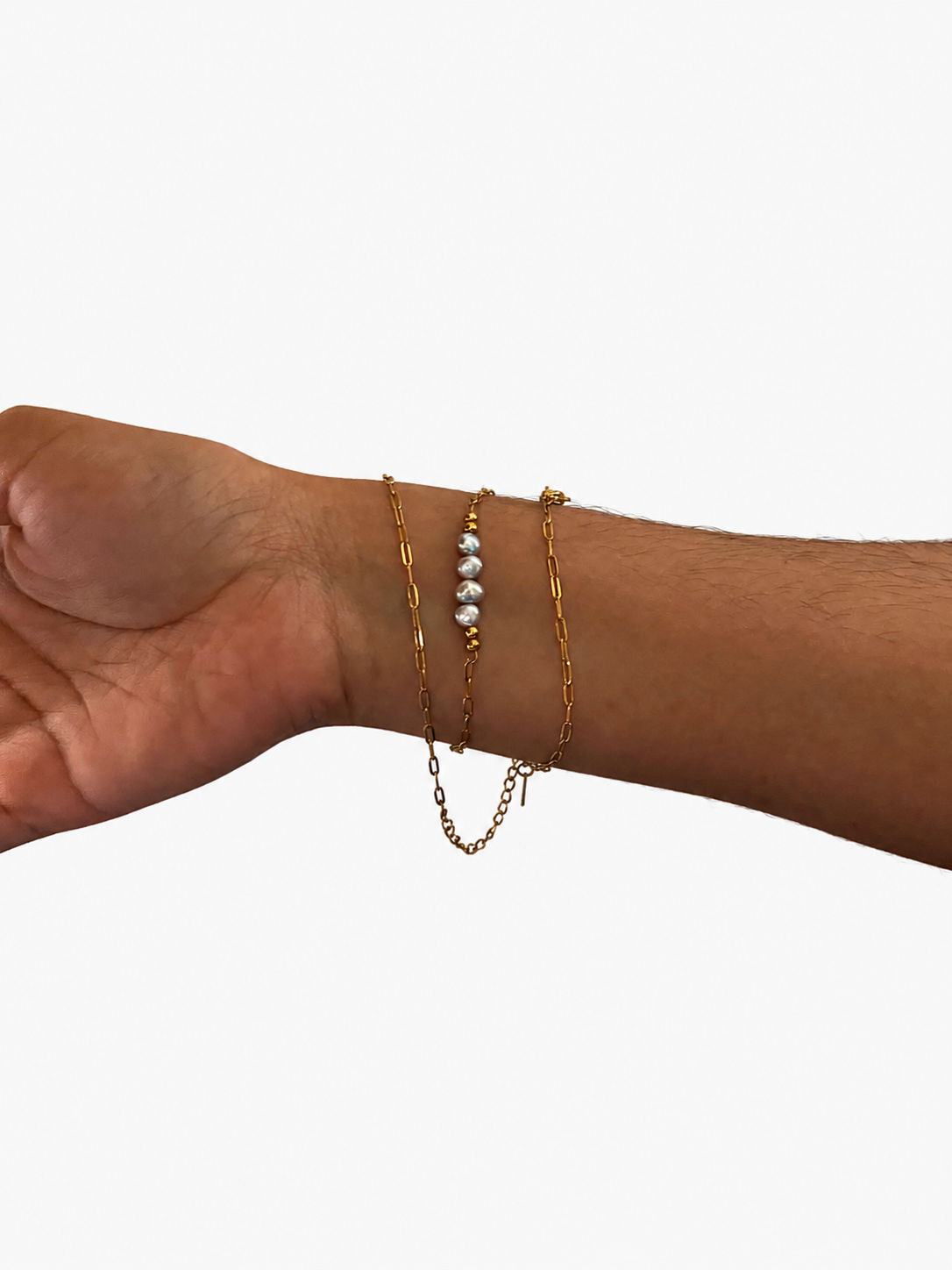 Grey baroque freshwater pearl necklace styled around the wrist with layered gold chains.