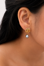 Close-up of a gold Nordic knot earring with a grey baroque freshwater pearl worn on the ear